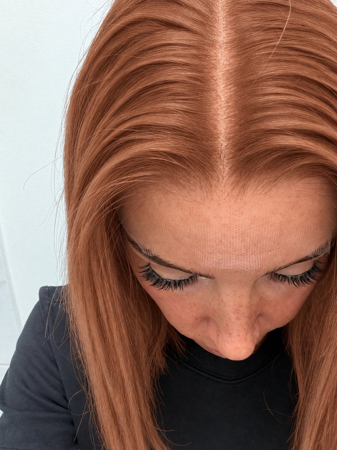 Close-up of the natural lace hairline and parting on a Copper Glow human hair wig in bright copper red